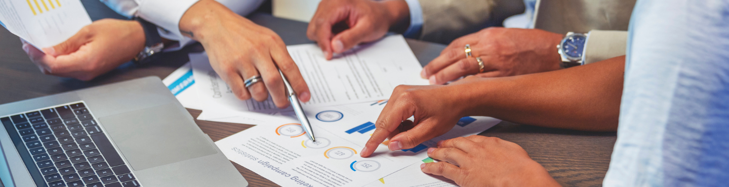 hands of three people shown reviewing a document